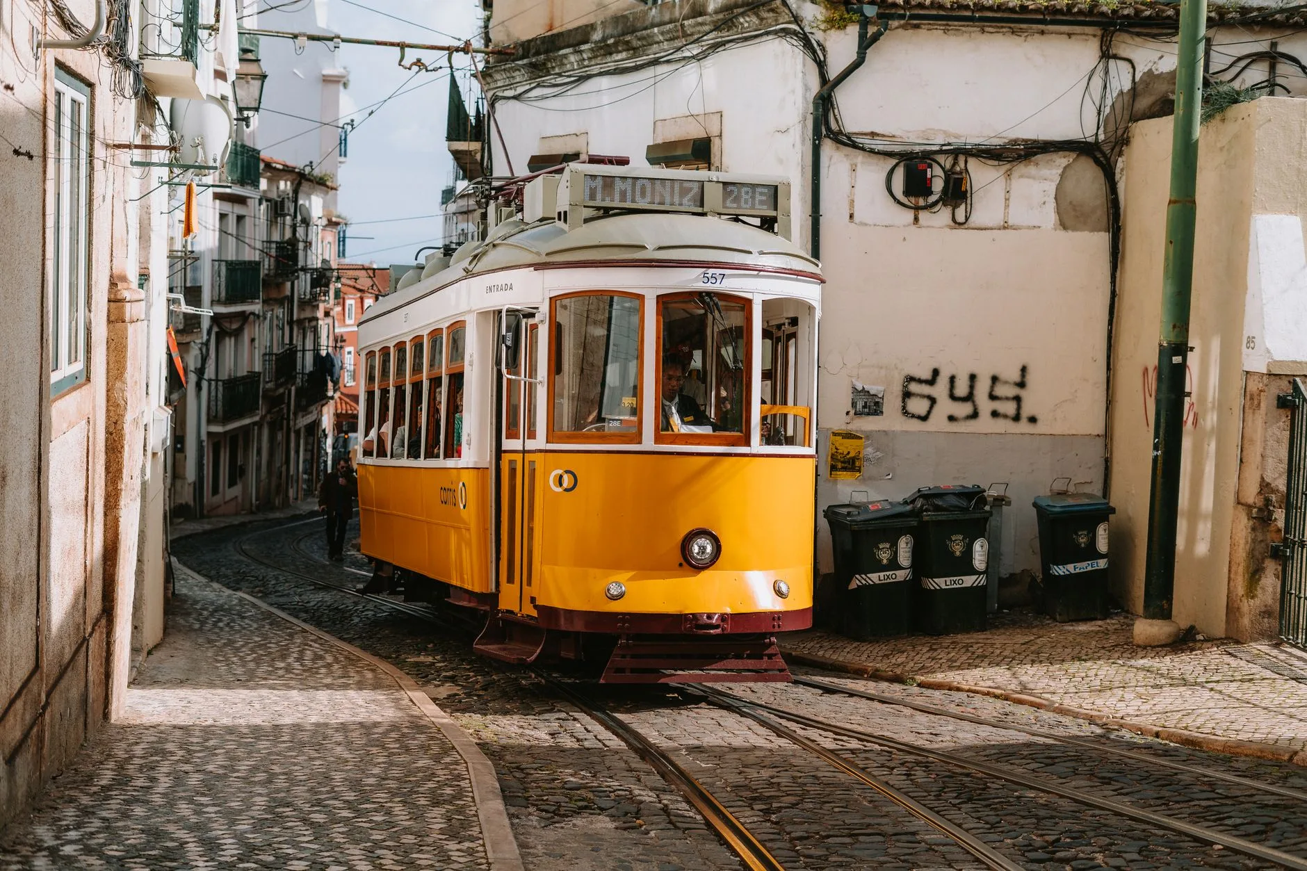 Tramway jaune dans une rue en pente de Lisbonne sous un ciel bleu